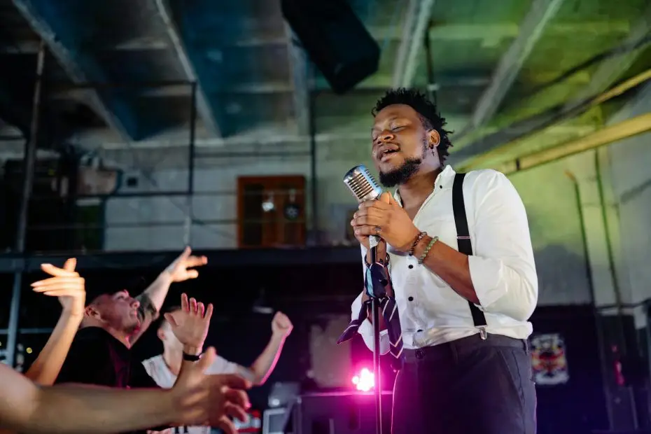 man in white dress shirt singing on stage