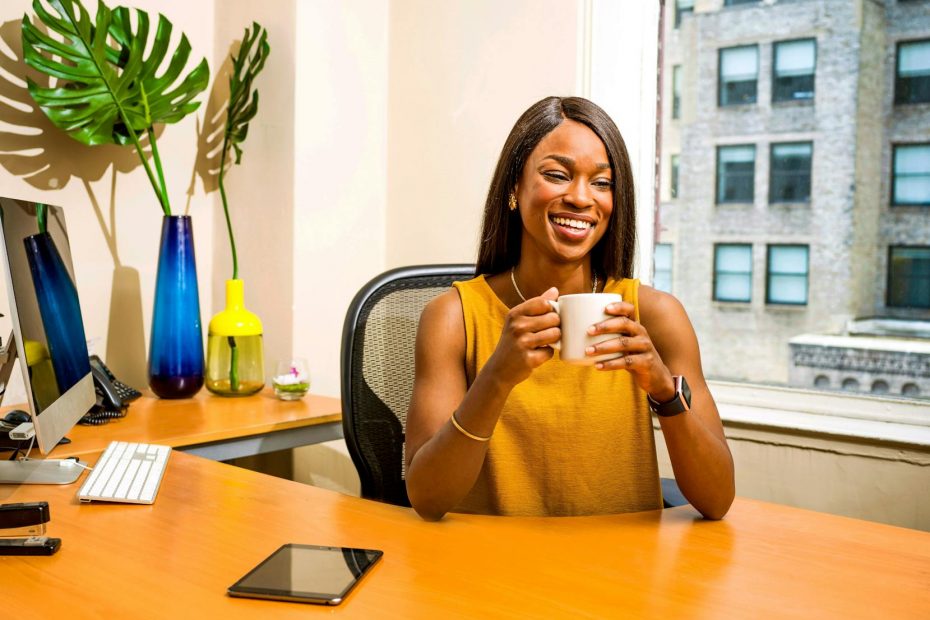 woman holding white ceramic mug at desk