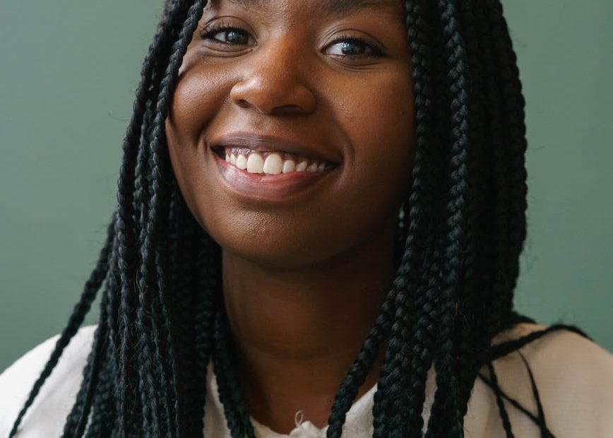 smiling black model with afro braids on gray background