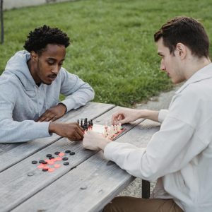 focused young diverse men playing chess in park