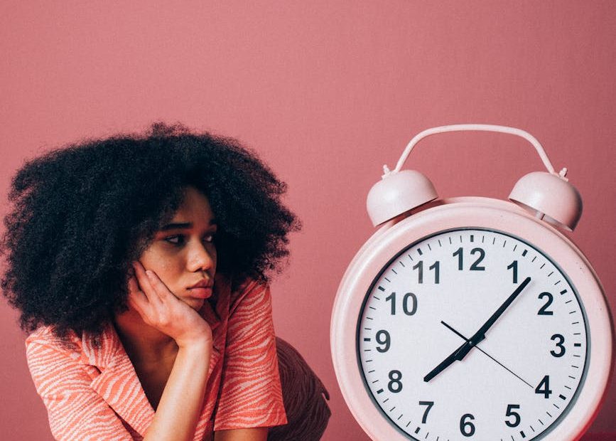 woman looking at a big pink alarm clock